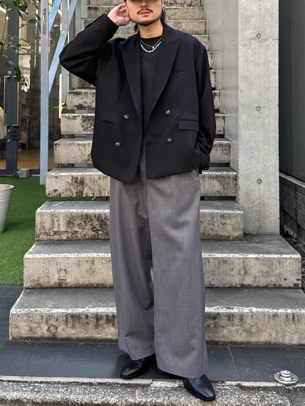 ブラック系のテーラードジャケット、ブラック系のニット/セーター、グレー系のスラックスを着用したメンズの春コーディネートの2枚目の写真