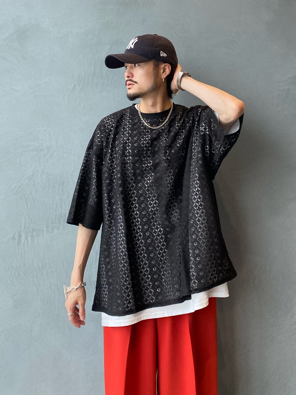 ブラック系のトップス、オレンジ系のスラックスを着用したメンズの夏コーディネートの2枚目の写真