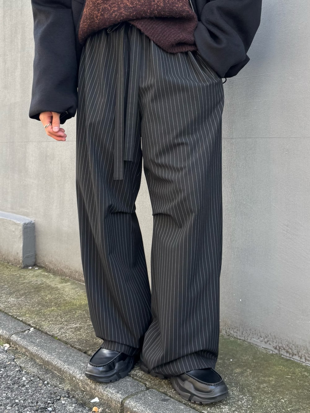 ブラウン系のニット/セーター、ブラック系のその他パンツ、ブラック系のローファーを着用したメンズの秋コーディネートの9枚目の写真