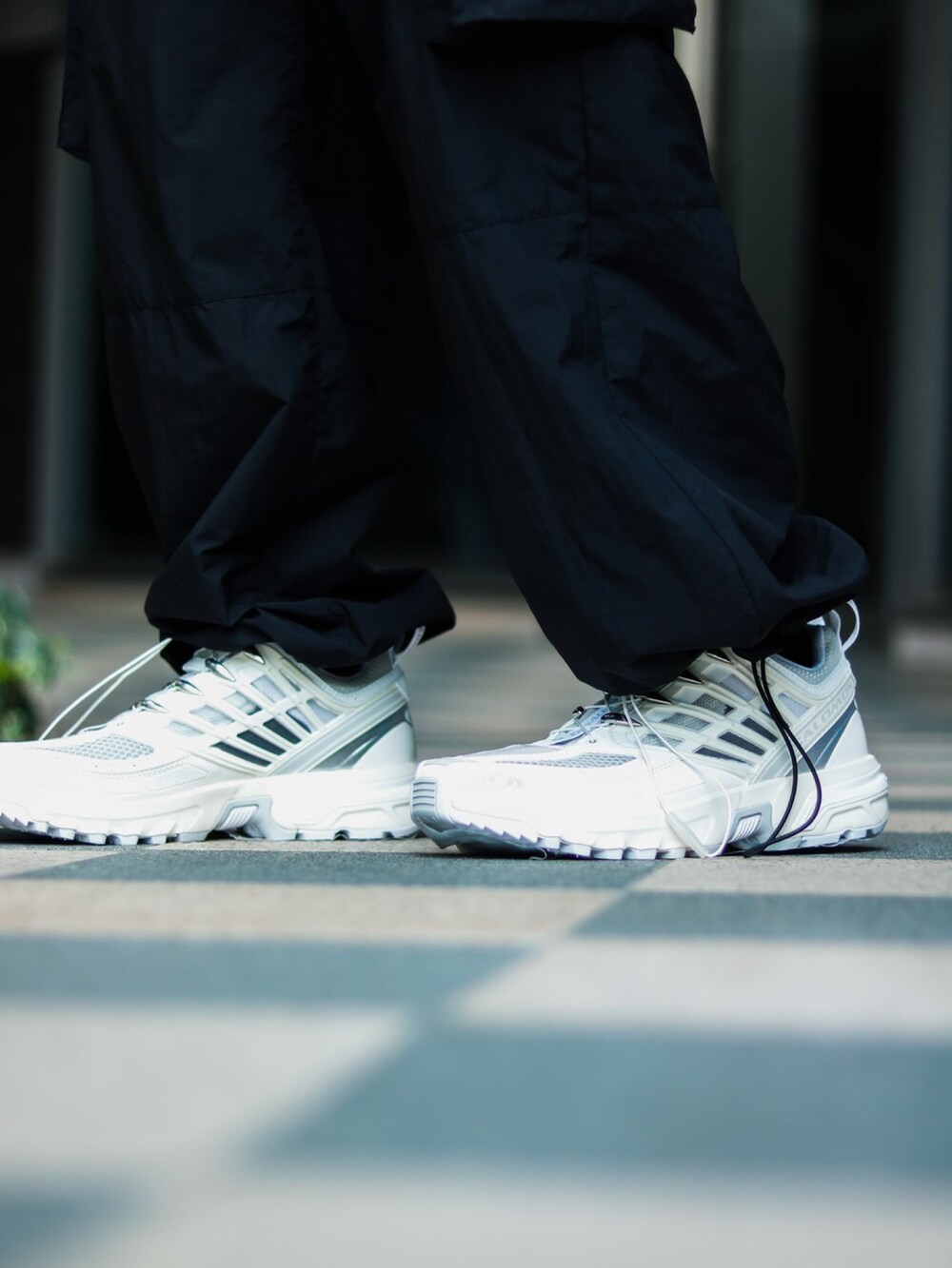 ブラック系のブルゾン、ブラック系のカーゴパンツ、ホワイト系のスニーカーを着用したメンズの春コーディネートの4枚目の写真