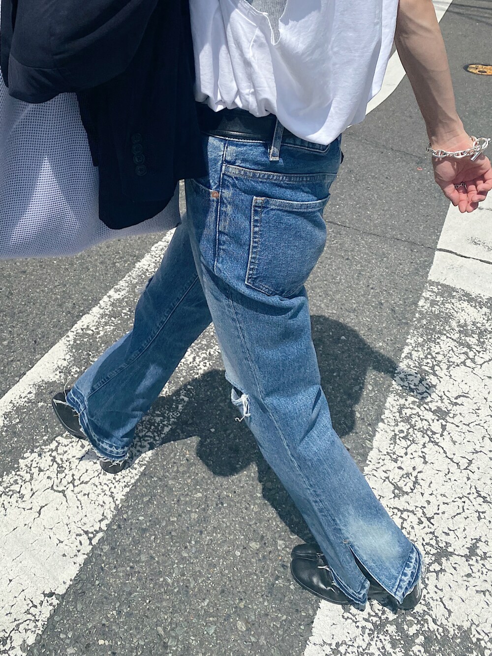 ホワイト系のTシャツ/カットソー、ブルー系のデニムパンツ、ホワイト系のバッグを着用したメンズの秋コーディネートの4枚目の写真