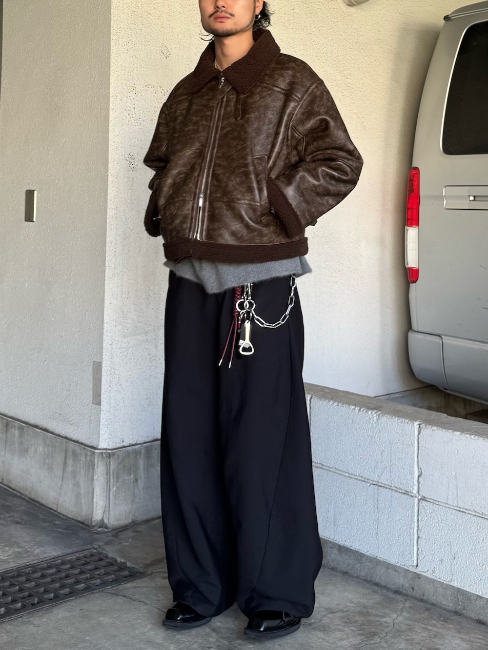 ブラック系のスラックス、グレー系のニット/セーター、ブラウン系のブルゾンを着用したメンズの秋コーディネートの5枚目の写真