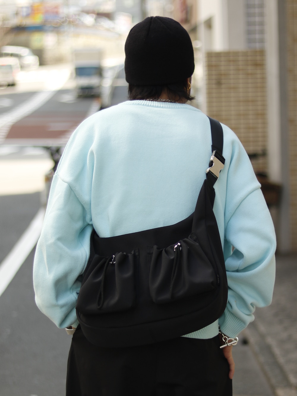 ブルー系のニット/セーター、ホワイト系のその他パンツ、ブラック系のショルダーバッグを着用したメンズの春コーディネートの3枚目の写真