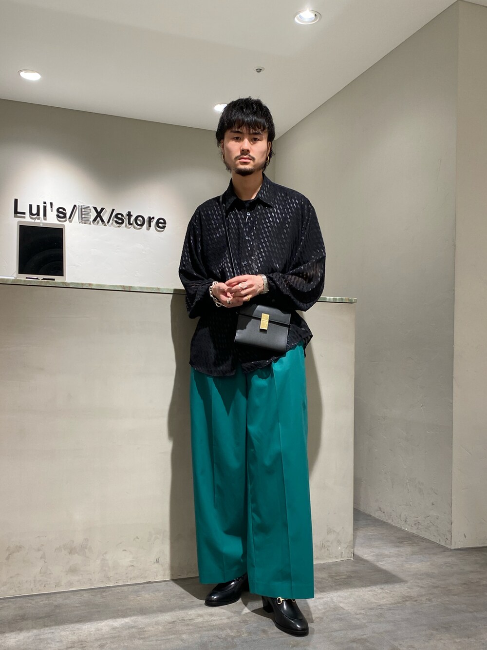 ブラック系のシャツ/ブラウス、ブラック系のショルダーバッグ、グリーン系のスラックスを着用したメンズの春コーディネートの2枚目の写真