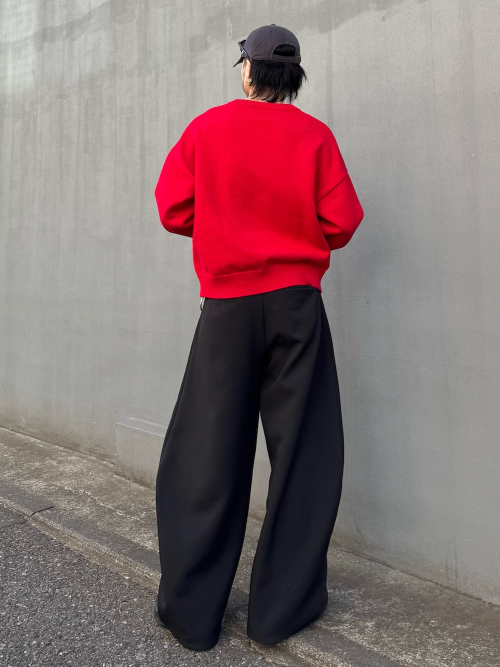 レッド系のニット/セーター、ブラック系のスラックスを着用したメンズの冬コーディネートの3枚目の写真