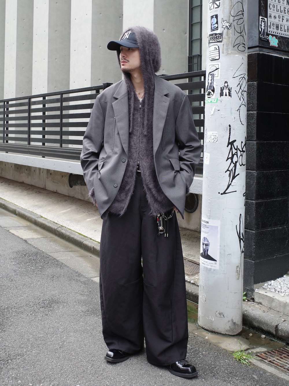 グレー系のテーラードジャケット、ブラック系のスラックス、グレー系のニット/セーターを着用したメンズの秋コーディネートの3枚目の写真