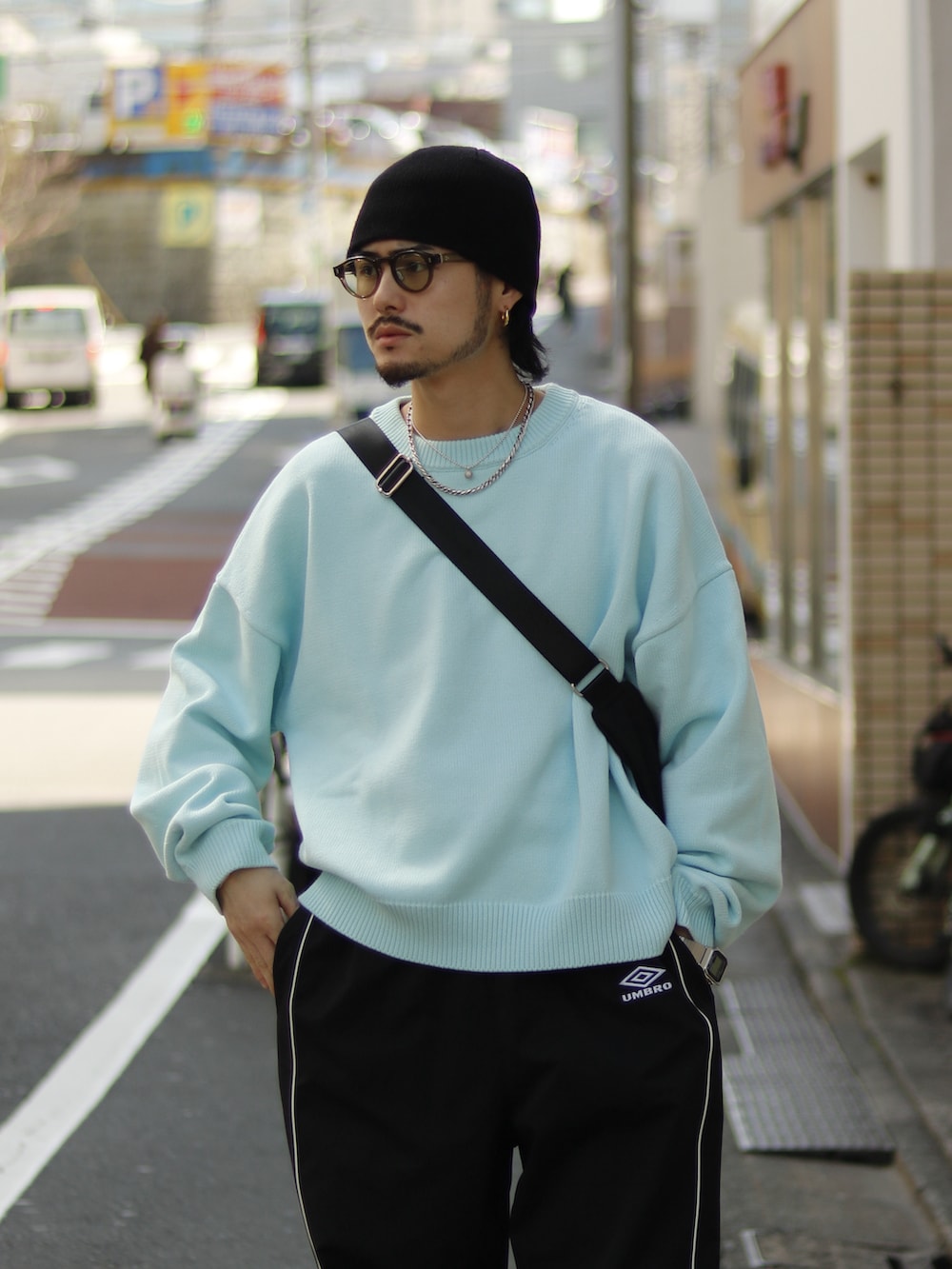 ブルー系のニット/セーター、ホワイト系のその他パンツ、ブラック系のショルダーバッグを着用したメンズの春コーディネートの2枚目の写真