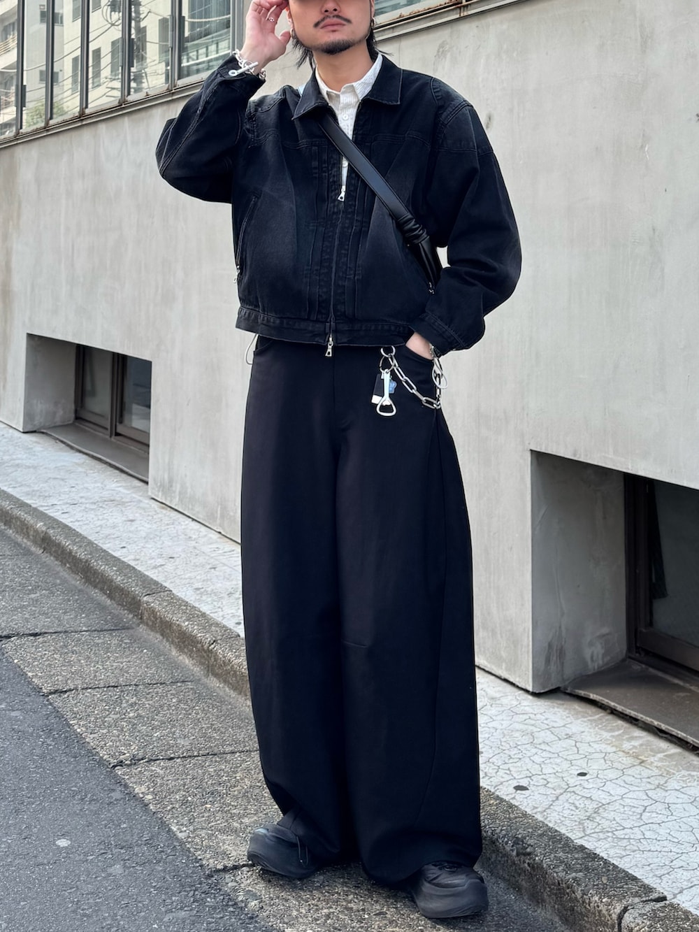 ブラック系のスラックス、ブラック系のショルダーバッグ、ホワイト系のシャツ/ブラウスを着用したメンズの春コーディネートの3枚目の写真