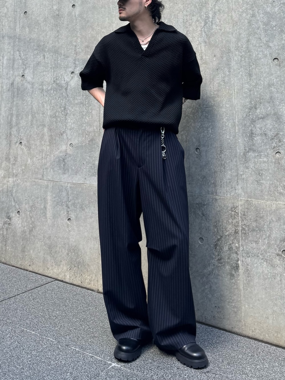ブラック系のニット/セーター、ブラック系のその他シューズ、ブルー系のスラックスを着用したメンズの夏コーディネートの3枚目の写真