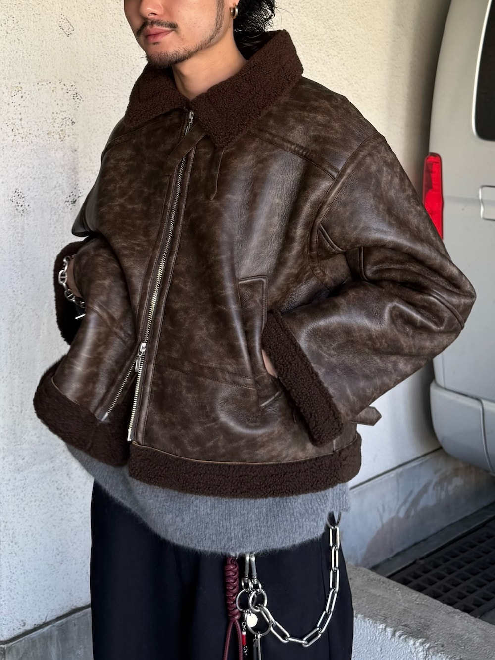 ブラック系のスラックス、グレー系のニット/セーター、ブラウン系のブルゾンを着用したメンズの秋コーディネートの7枚目の写真