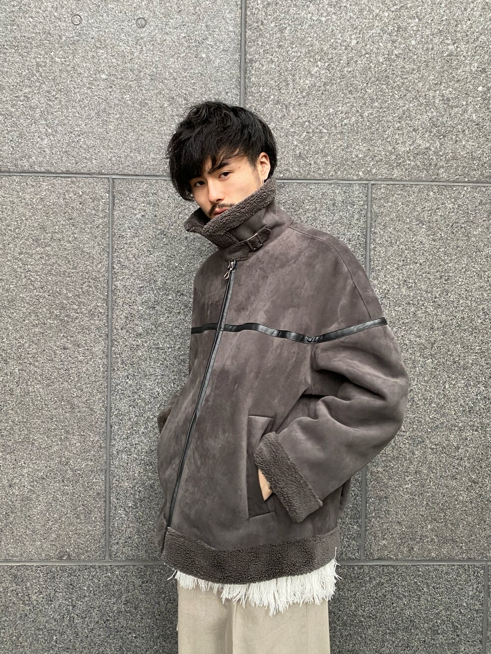 グレー系のブルゾン、ホワイト系のニット/セーター、ベージュ系のデニムパンツを着用したメンズの秋コーディネートの4枚目の写真