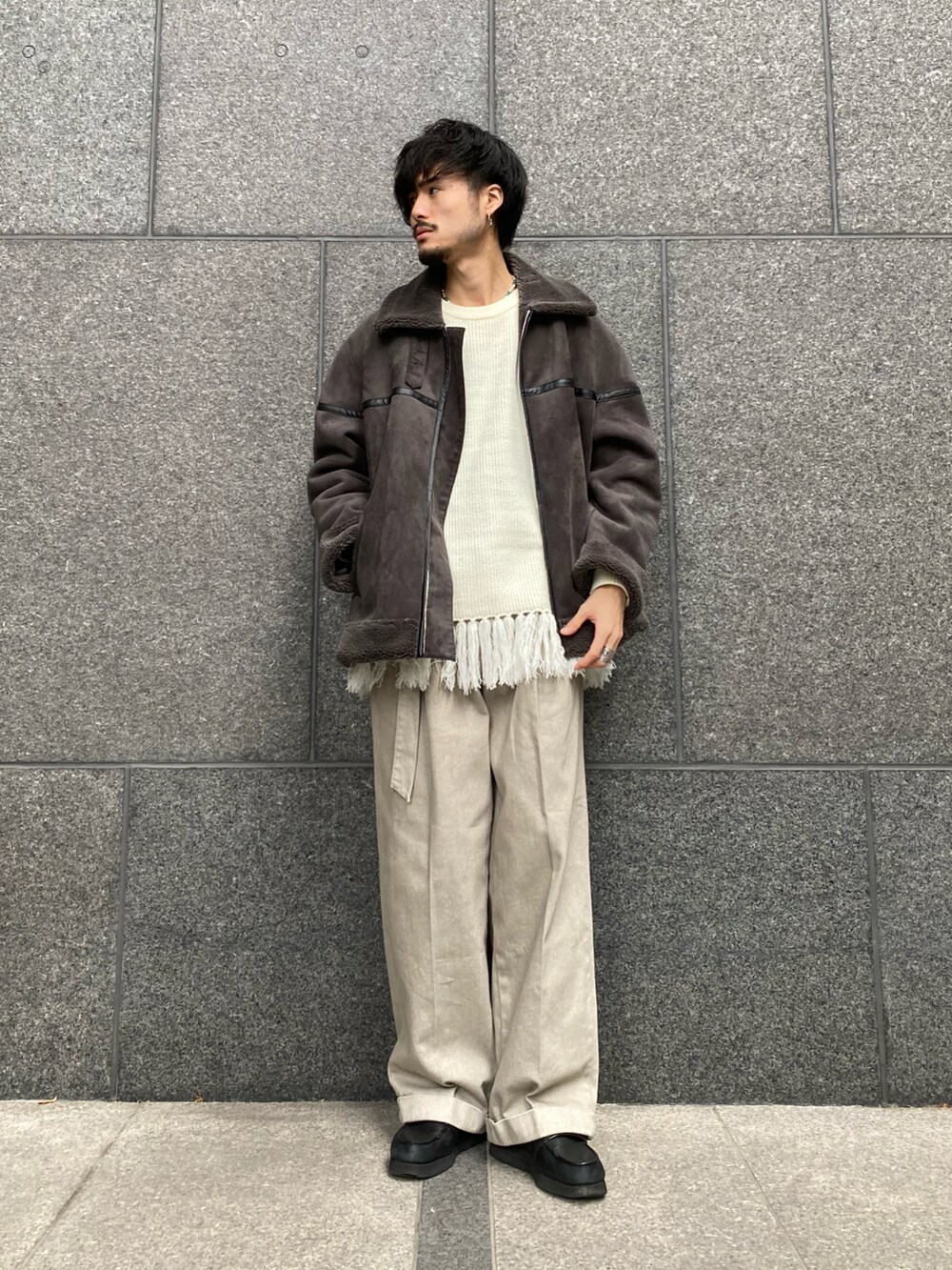 グレー系のブルゾン、ホワイト系のニット/セーター、ベージュ系のデニムパンツを着用したメンズの秋コーディネートの2枚目の写真