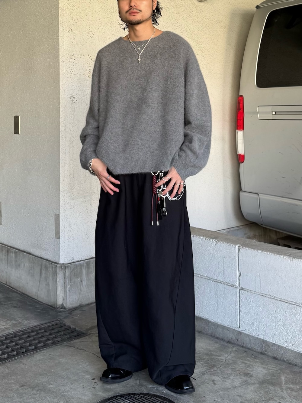 グレー系のニット/セーター、ブラック系のスラックスを着用したメンズの秋コーディネートの2枚目の写真