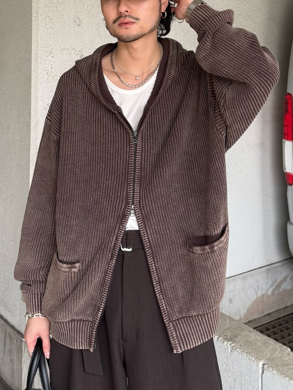 ブラウン系のパーカー、グレー系のスラックス、ブラック系のショルダーバッグを着用したメンズの春コーディネートの8枚目の写真