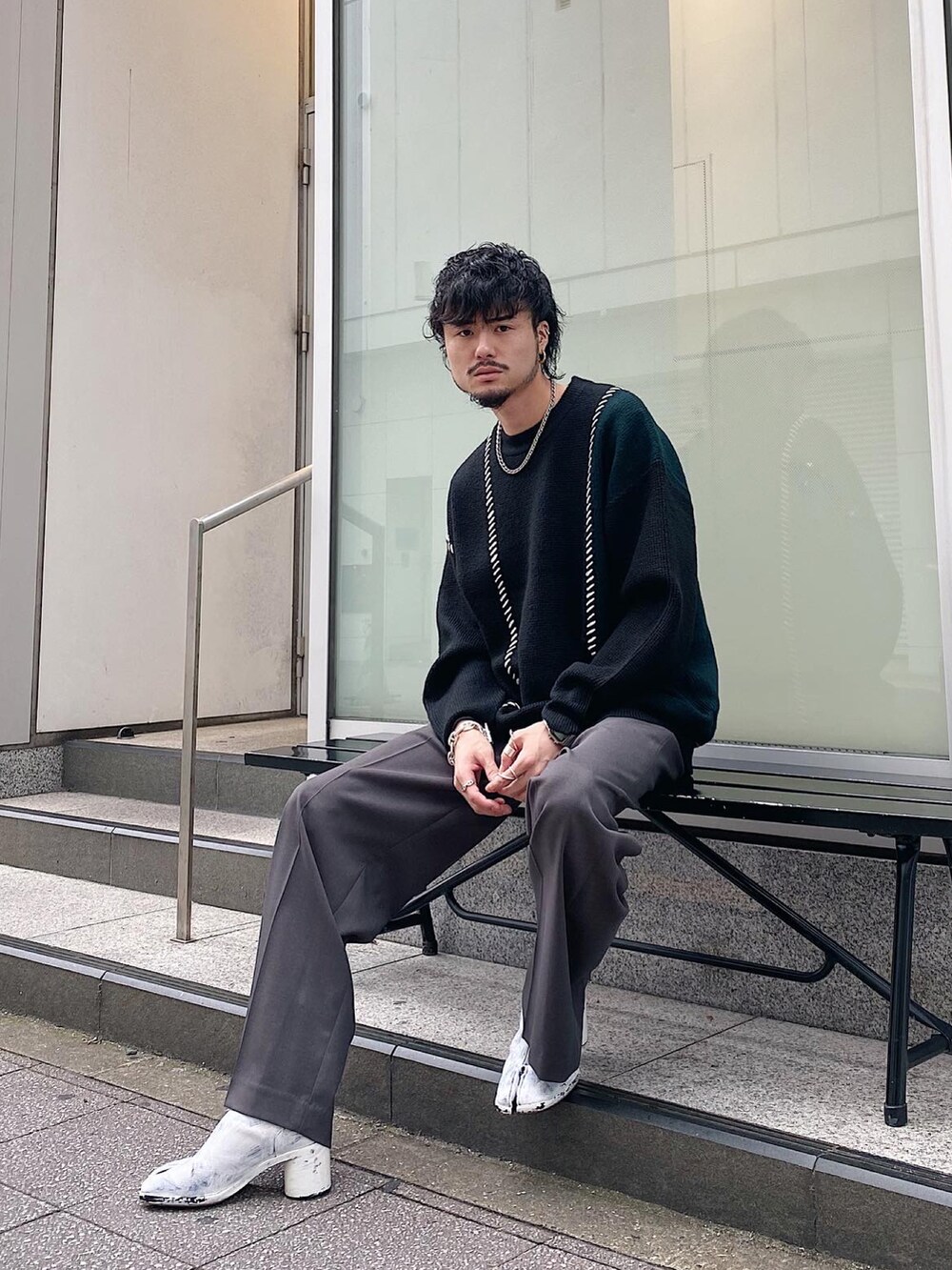 ブラック系のニット/セーター、グレー系のスラックスを着用したメンズの秋コーディネートの3枚目の写真