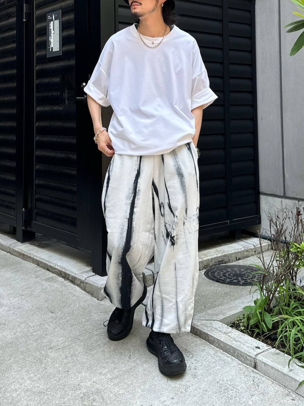 ホワイト系のTシャツ/カットソー、ホワイト系のスウェットパンツ、ブラック系のキャップを着用したメンズの夏コーディネートの2枚目の写真