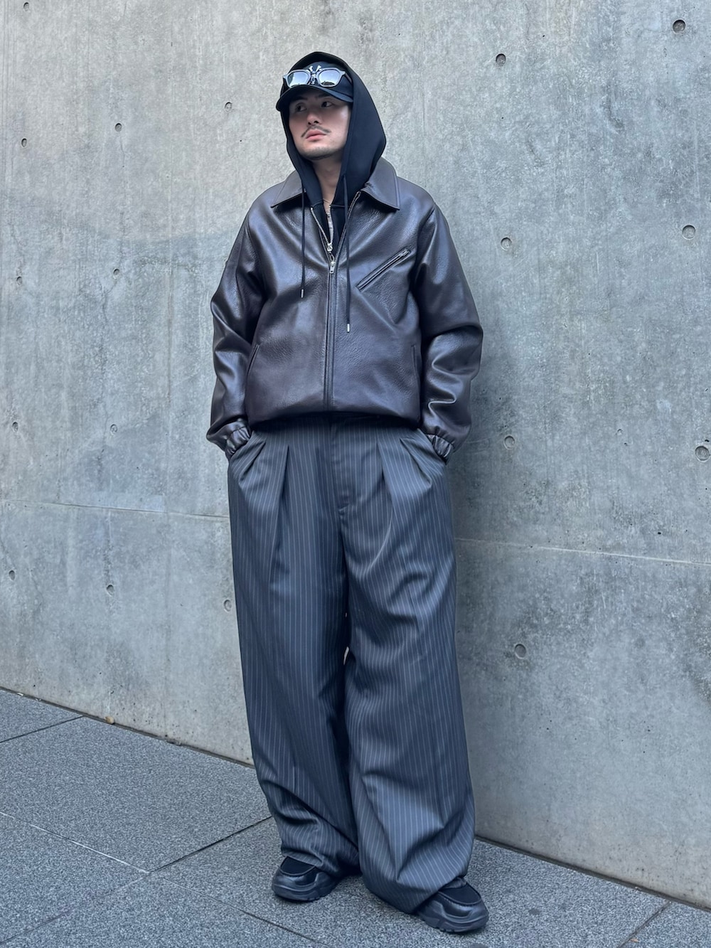 グレー系のスラックス、ブラック系のローファー、ブラック系のパーカーを着用したメンズの冬コーディネートの2枚目の写真