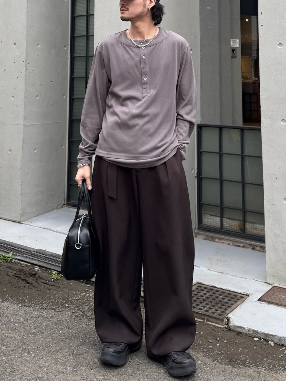 グレー系のスラックス、グレー系のTシャツ/カットソー、ブラック系のショルダーバッグを着用したメンズの春コーディネートの4枚目の写真