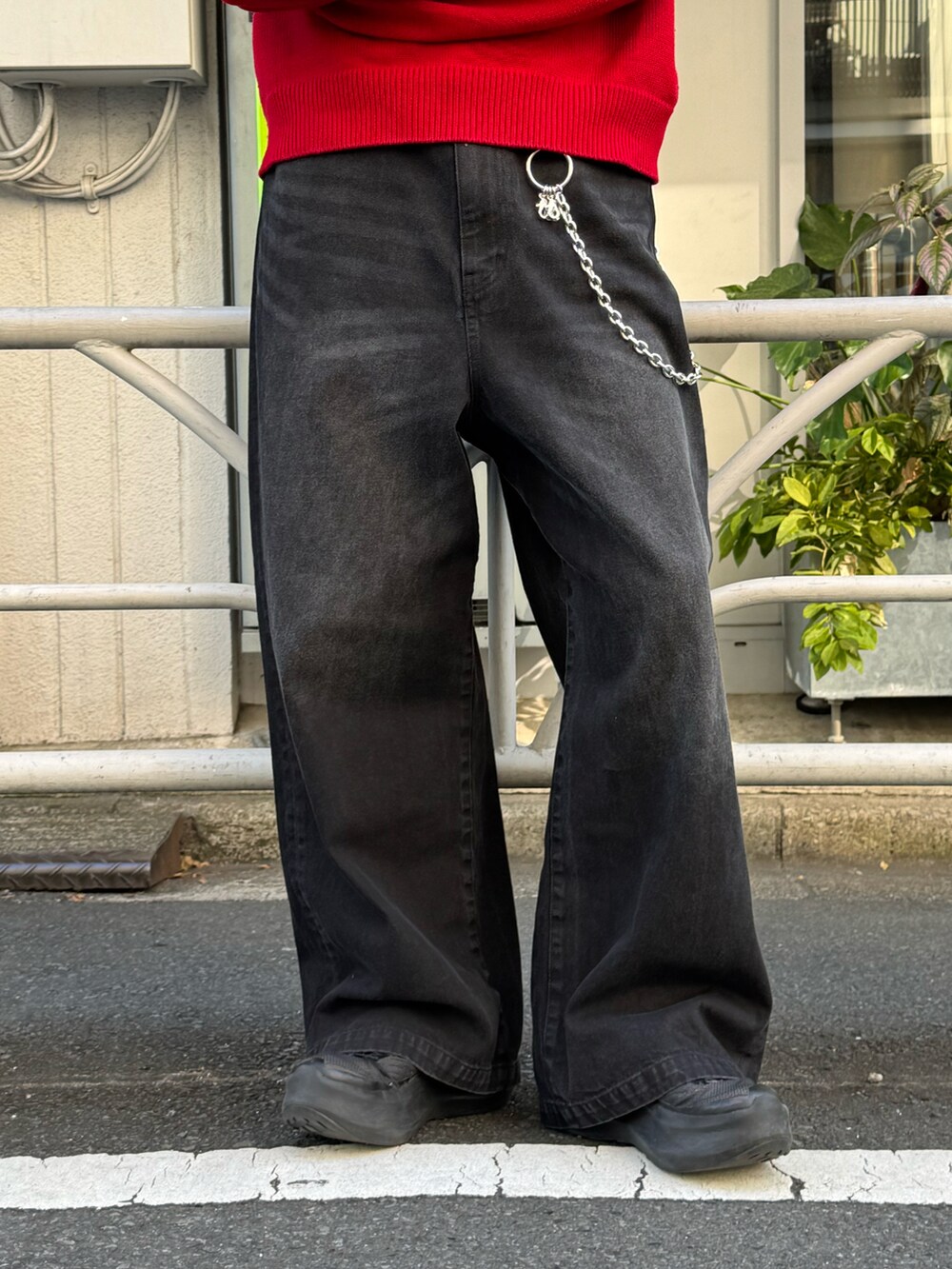 レッド系のニット/セーター、ブラック系のデニムパンツ、シルバー系の財布/小物を着用したメンズの冬コーディネートの5枚目の写真