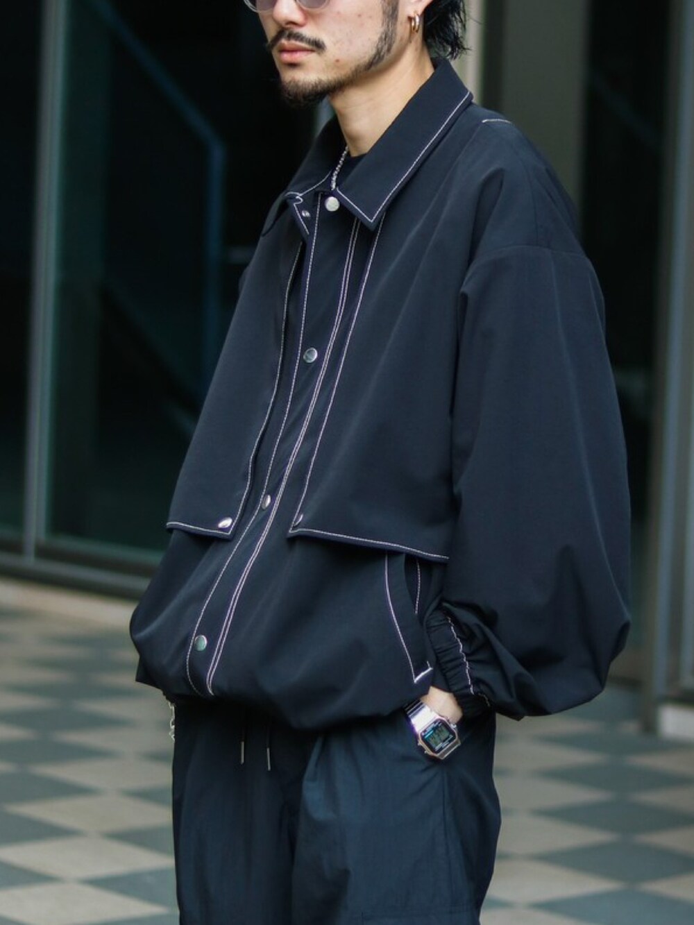 ブラック系のブルゾン、ブラック系のカーゴパンツ、ホワイト系のスニーカーを着用したメンズの春コーディネートの2枚目の写真