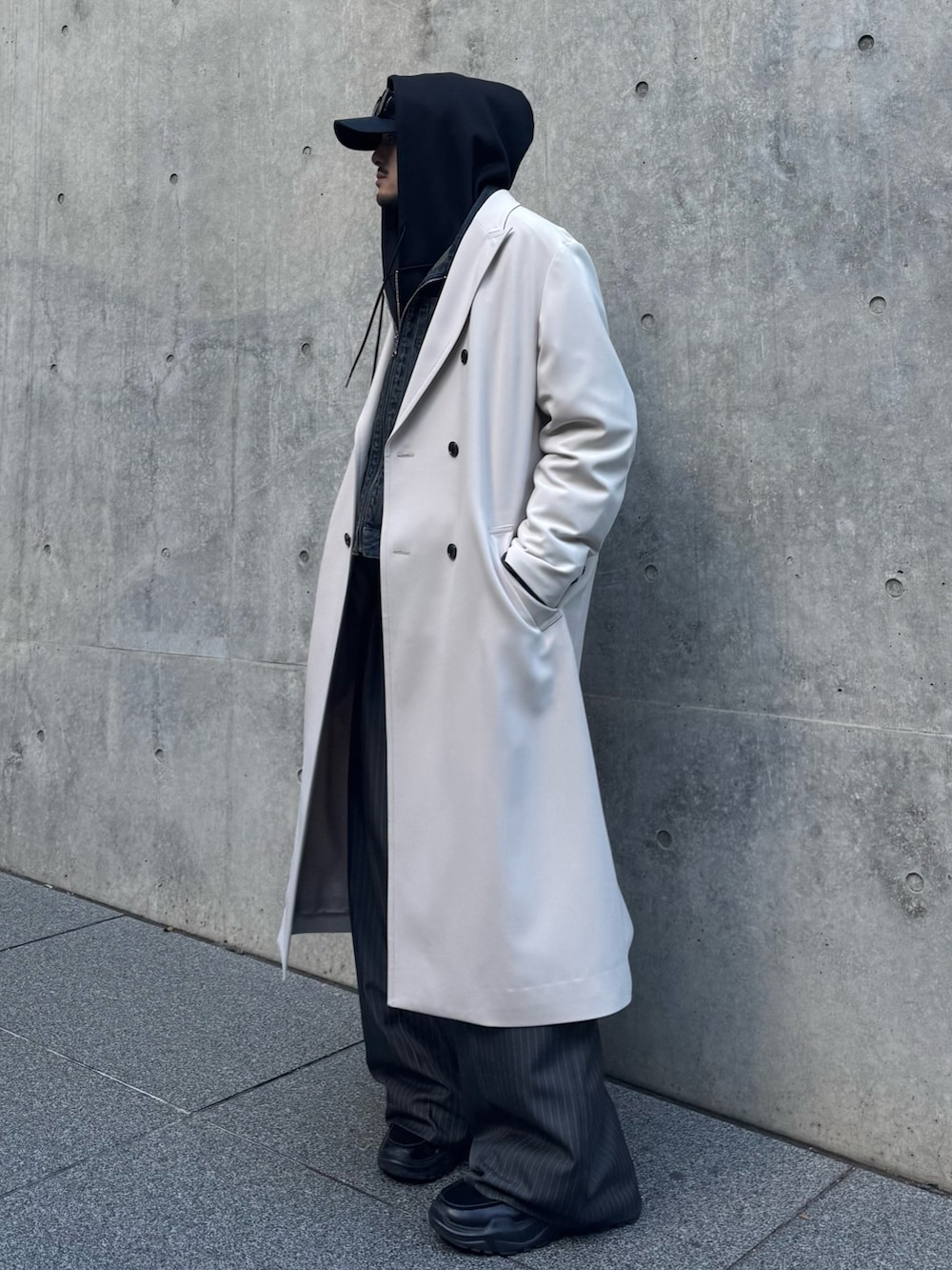 グレー系のチェスターコート、ブルー系のデニムジャケット、ブラック系のパーカーを着用したメンズの冬コーディネートの3枚目の写真