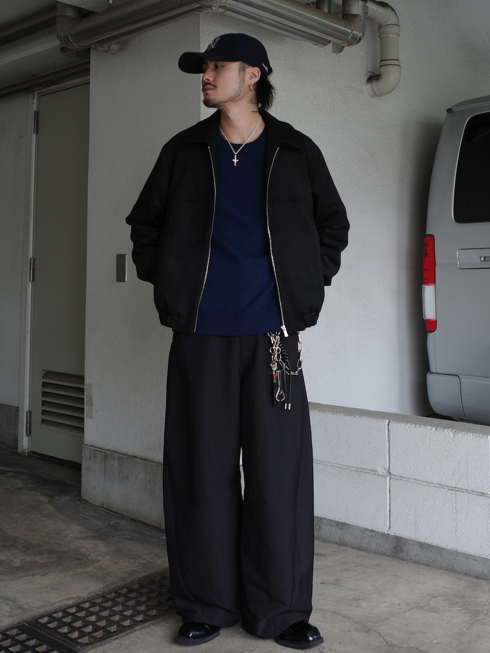 ブラック系のブルゾン、ブルー系のニット/セーター、ブラック系のスラックスを着用したメンズの冬コーディネートの2枚目の写真