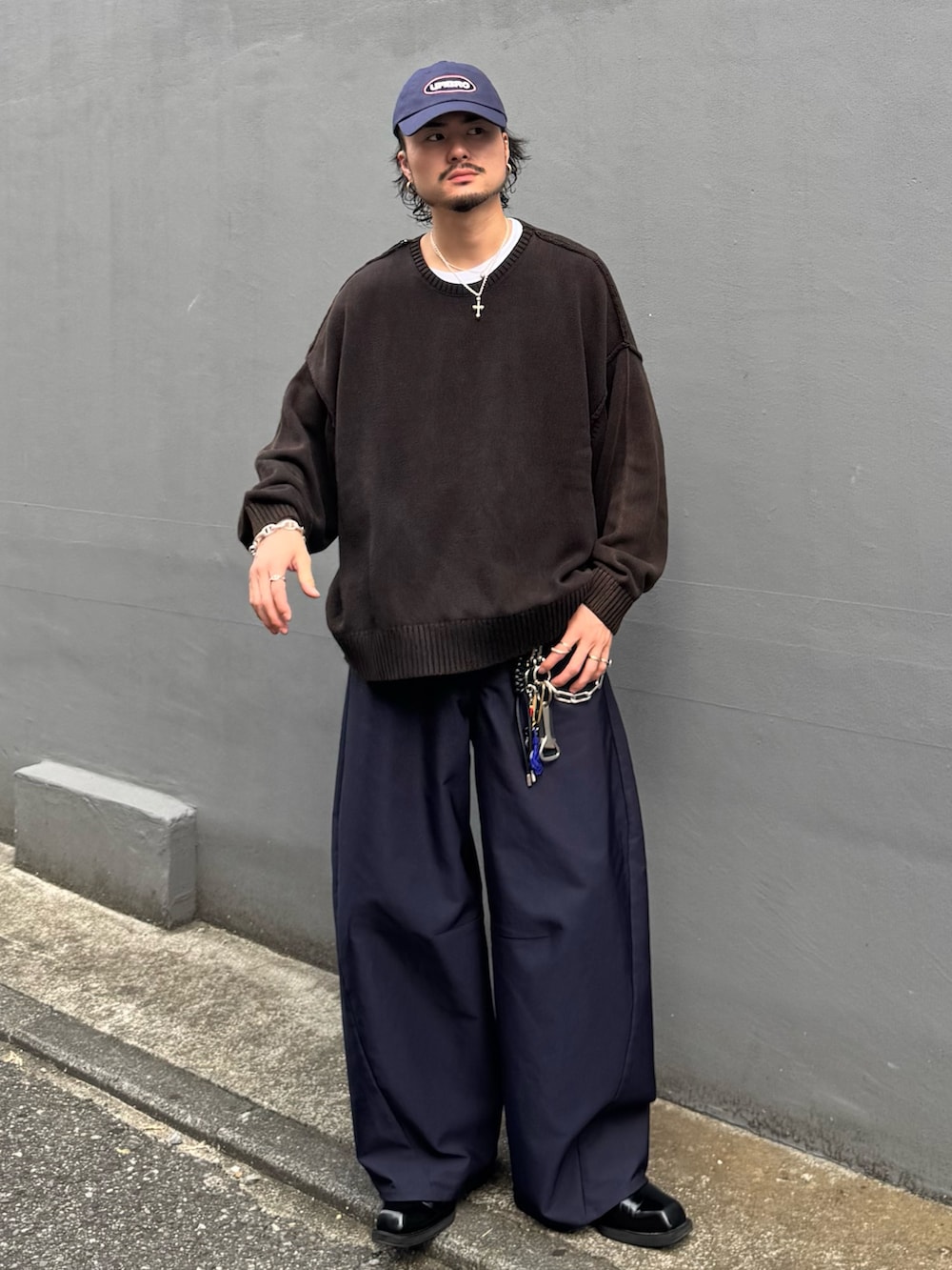 ブラック系のニット/セーター、ブルー系のスラックス、ブルー系のキャップを着用したメンズの秋コーディネートの2枚目の写真