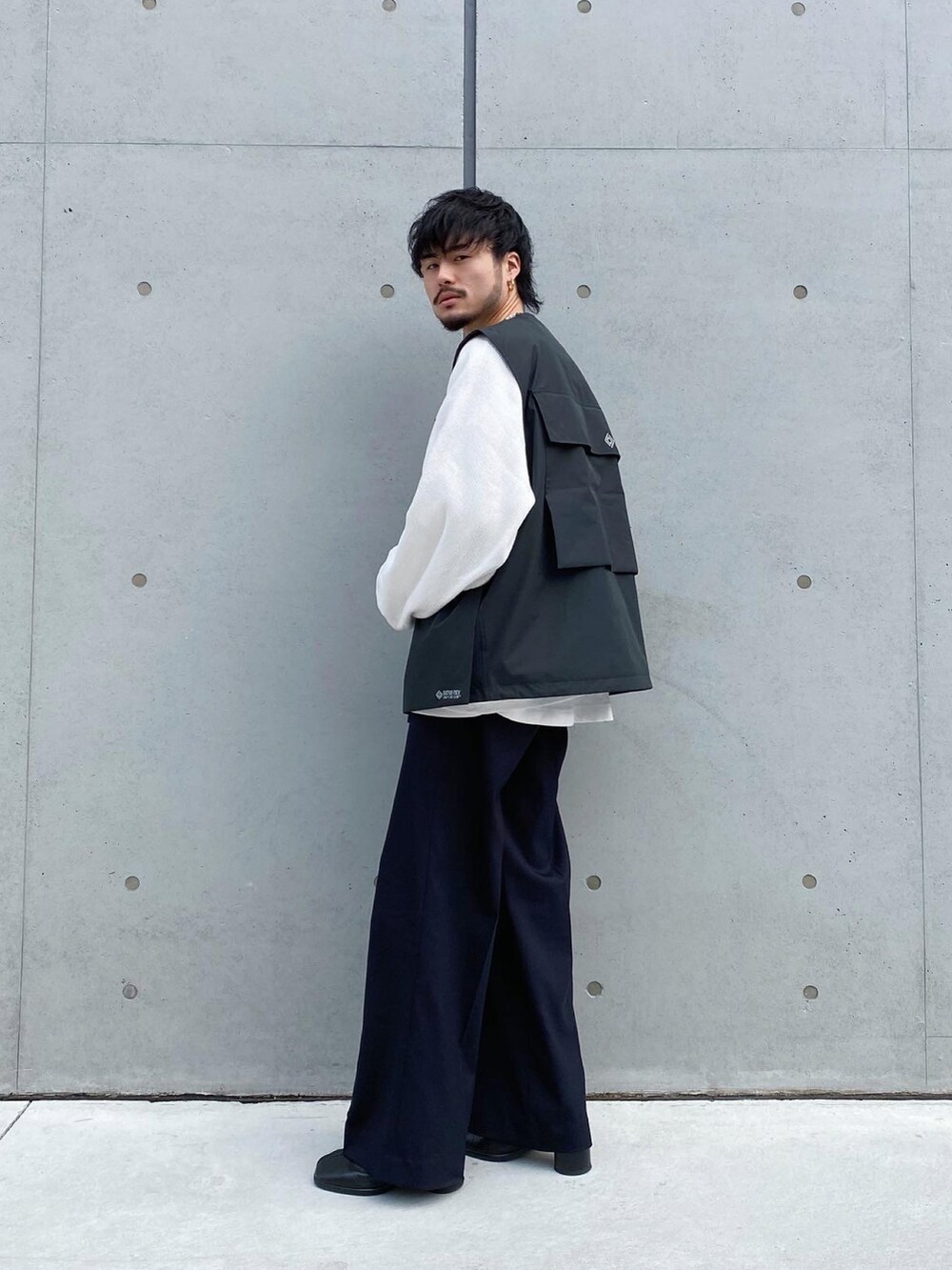 ブラック系のベスト、ブラック系のスラックス、ブラック系のブーツを着用したメンズの冬コーディネートの2枚目の写真