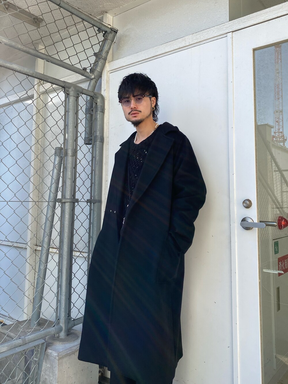 ブラック系のチェスターコート、ブラック系のニット/セーター、ブラック系のスラックスを着用したメンズの冬コーディネートの3枚目の写真