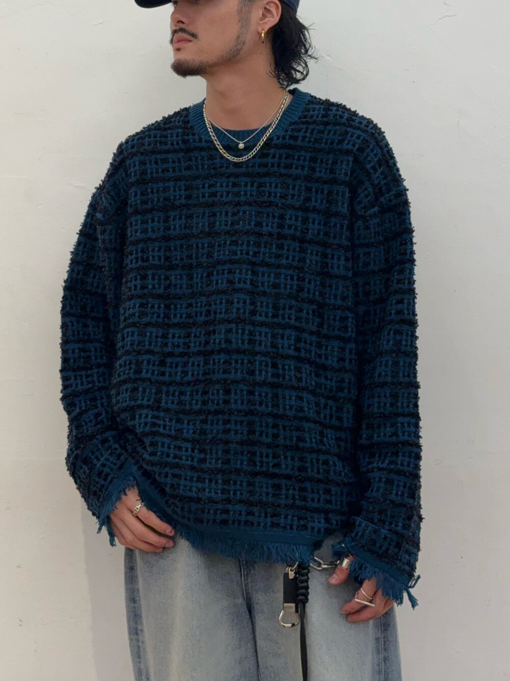 ブルー系のニット/セーター、ブルー系のデニムパンツ、ブラック系のブーツを着用したメンズの秋コーディネートの2枚目の写真