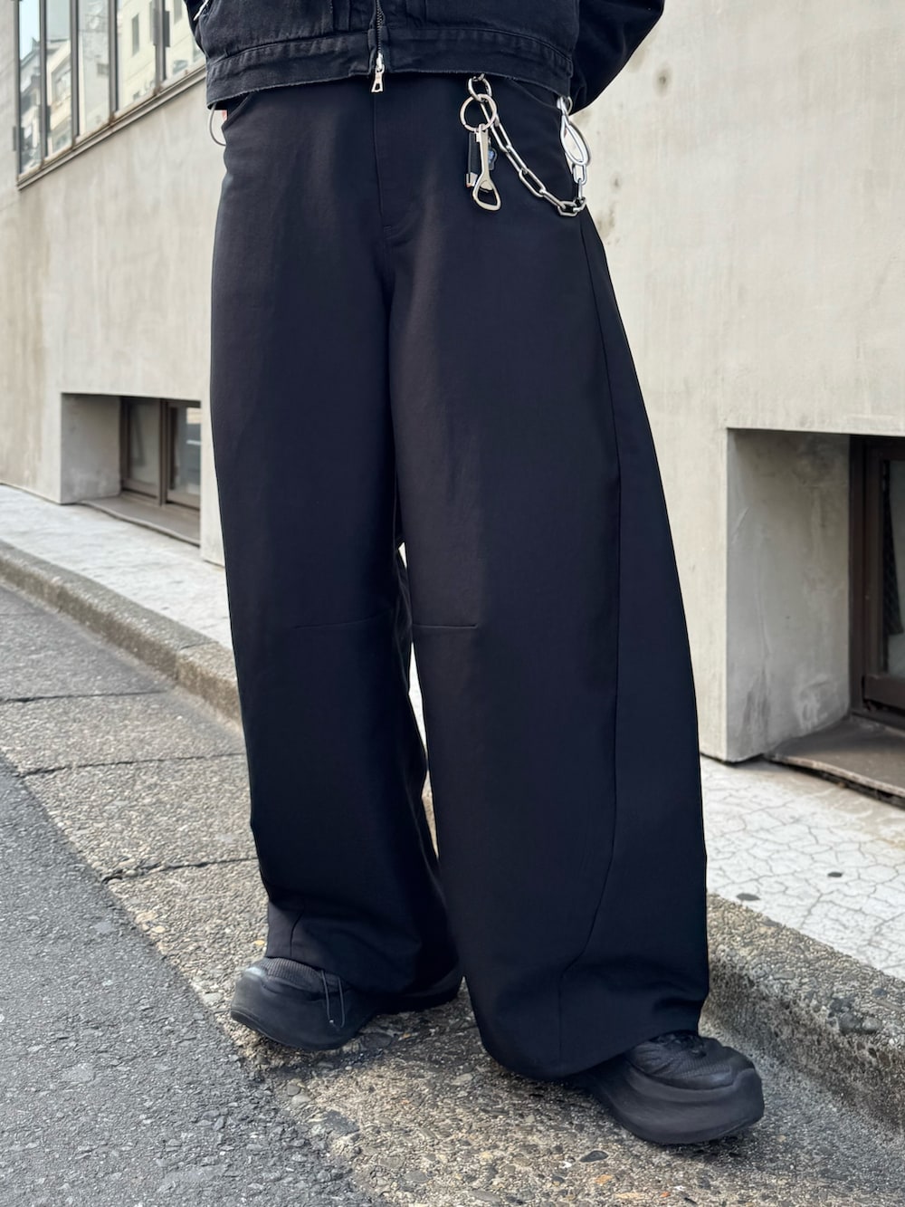 ブラック系のスラックス、ブラック系のショルダーバッグ、ホワイト系のシャツ/ブラウスを着用したメンズの春コーディネートの5枚目の写真