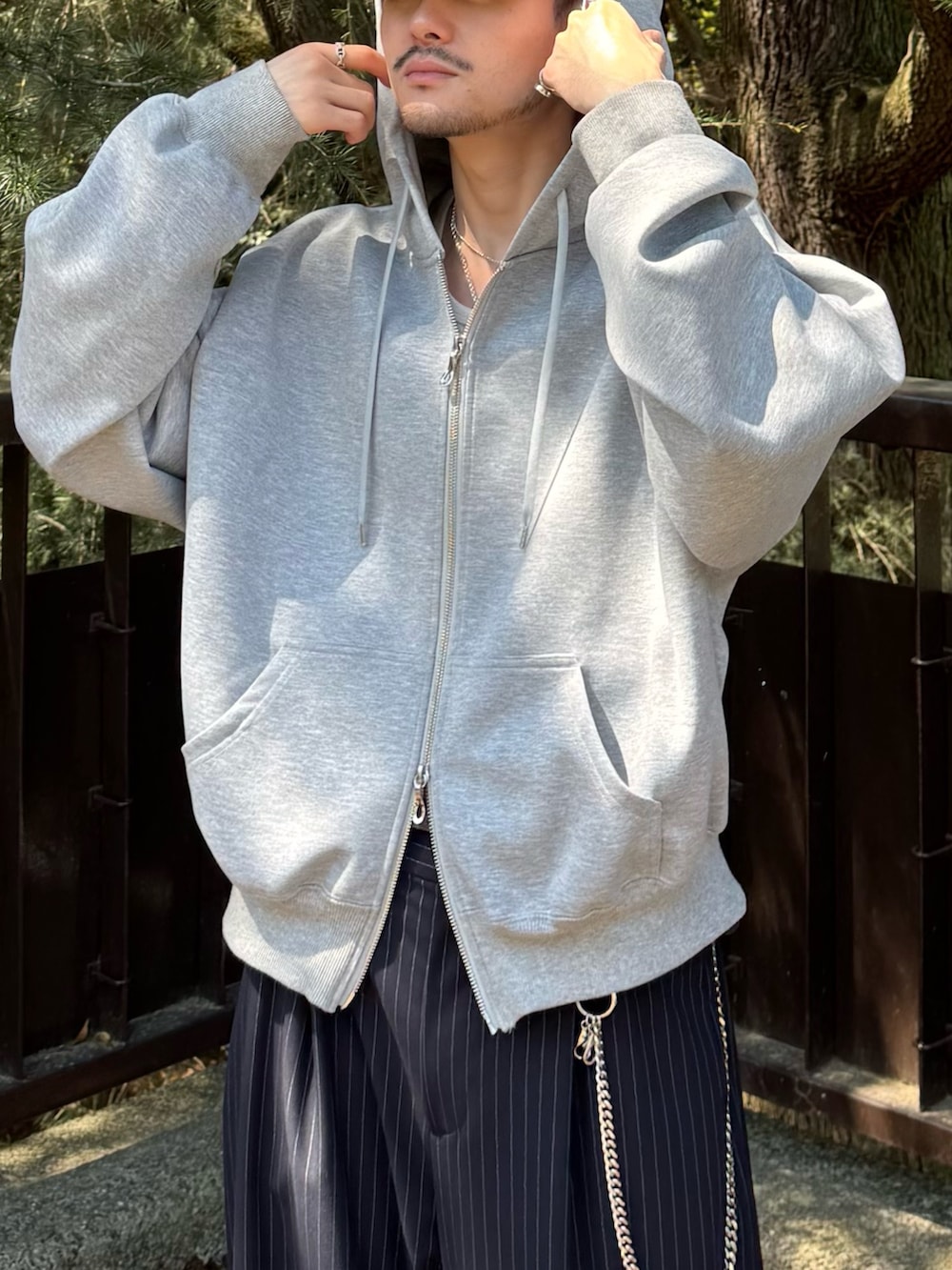 グレー系のパーカー、ブルー系のスラックス、シルバー系のウォレットチェーンを着用したメンズの春コーディネートの5枚目の写真