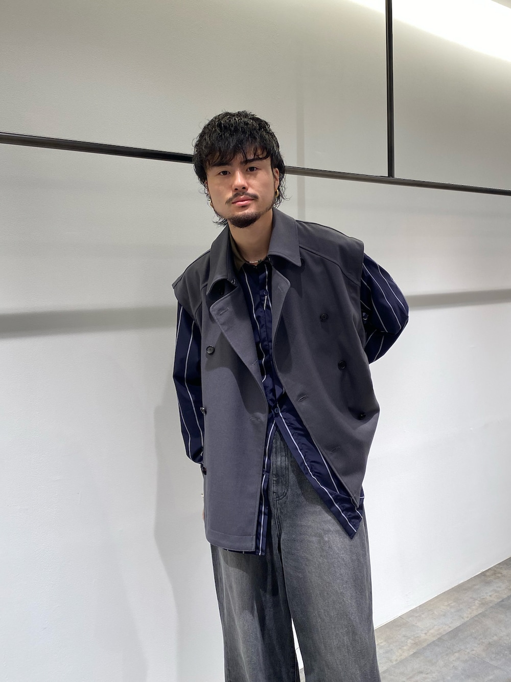 グレー系のベスト、ブルー系のシャツ/ブラウス、ブラック系のデニムパンツを着用したメンズの秋コーディネートの3枚目の写真