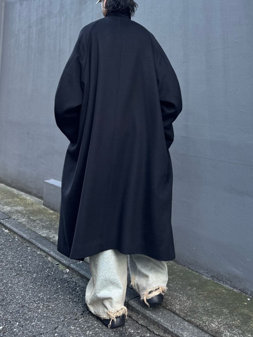 ブルー系のニット/セーター、ブルー系のデニムパンツ、ブラック系のステンカラーコートを着用したメンズの秋コーディネートの7枚目の写真