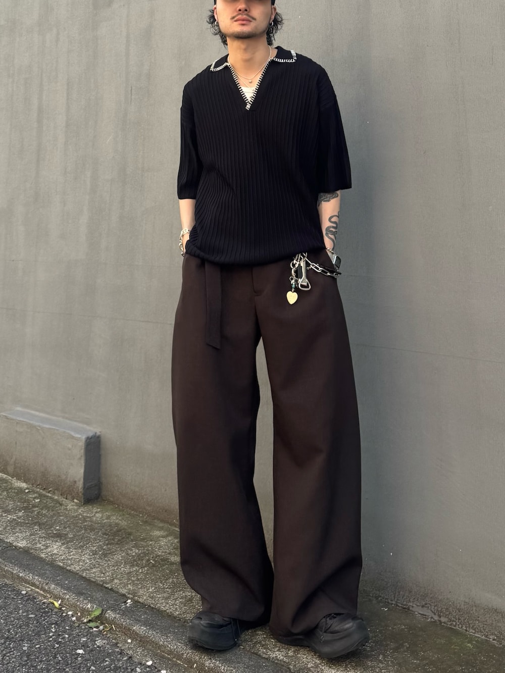 ブラック系のニット/セーター、グレー系のスラックスを着用したメンズの春コーディネートの3枚目の写真