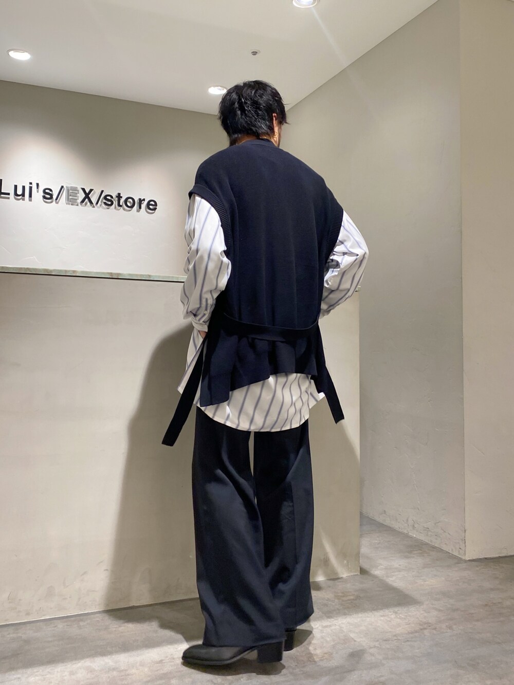 ブラック系のベスト、ホワイト系のシャツ/ブラウス、ブラック系のスラックスを着用したメンズの春コーディネートの2枚目の写真