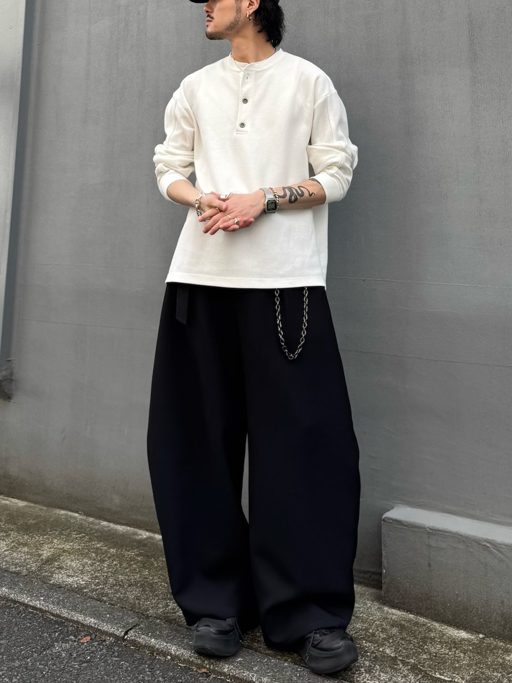 ホワイト系のTシャツ/カットソー、ブラック系のスラックス、ブラック系のウォレットチェーンを着用したメンズの春コーディネートの3枚目の写真
