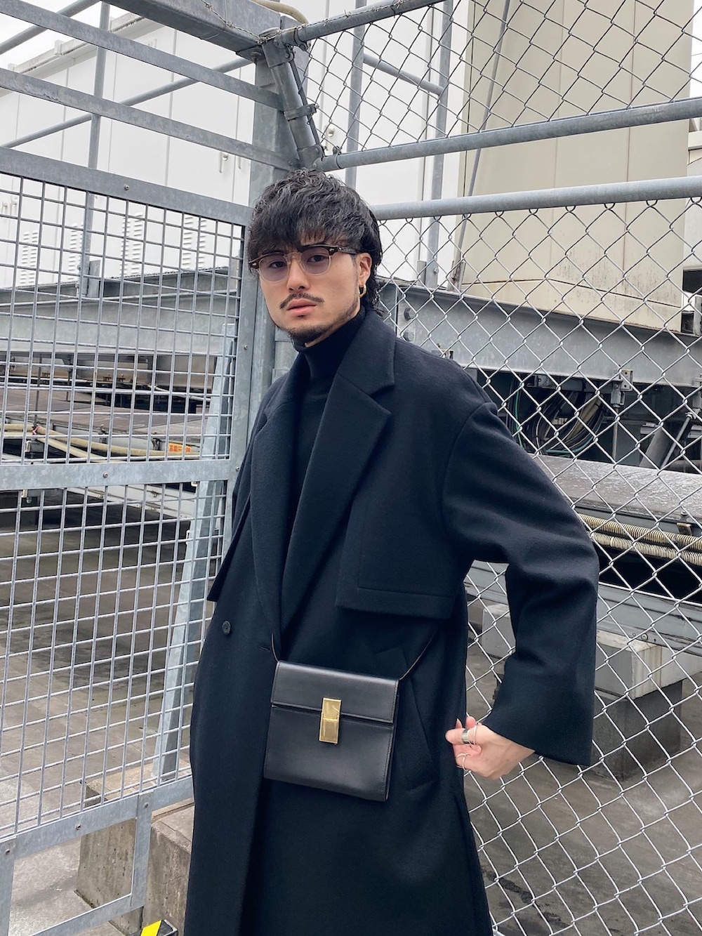 ブラック系のチェスターコート、ブラック系のショルダーバッグ、グレー系のスラックスを着用したメンズの冬コーディネートの5枚目の写真