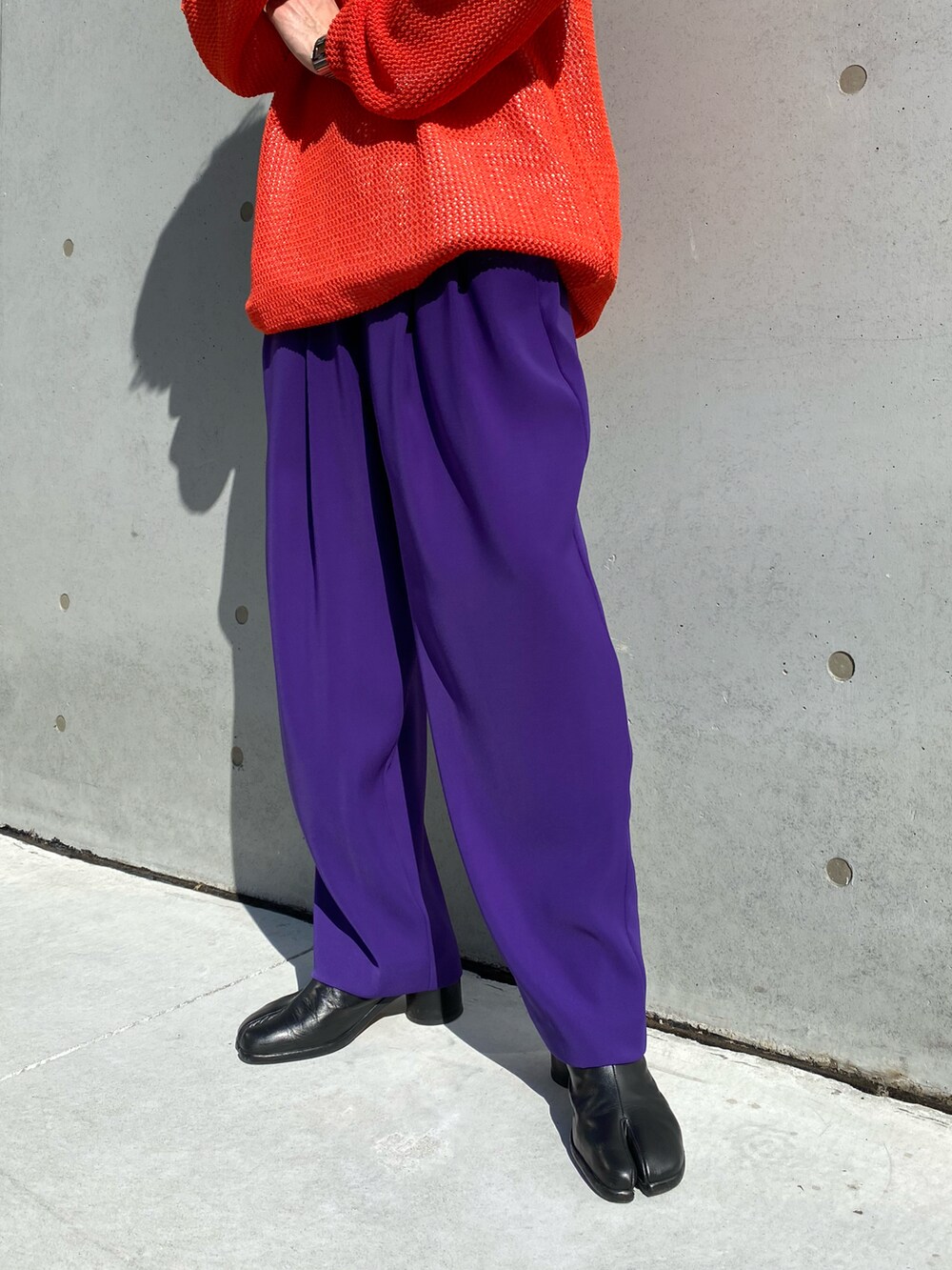 ブラック系のトレンチコート、オレンジ系のニット/セーター、パープル系のスラックスを着用したメンズの冬コーディネートの2枚目の写真