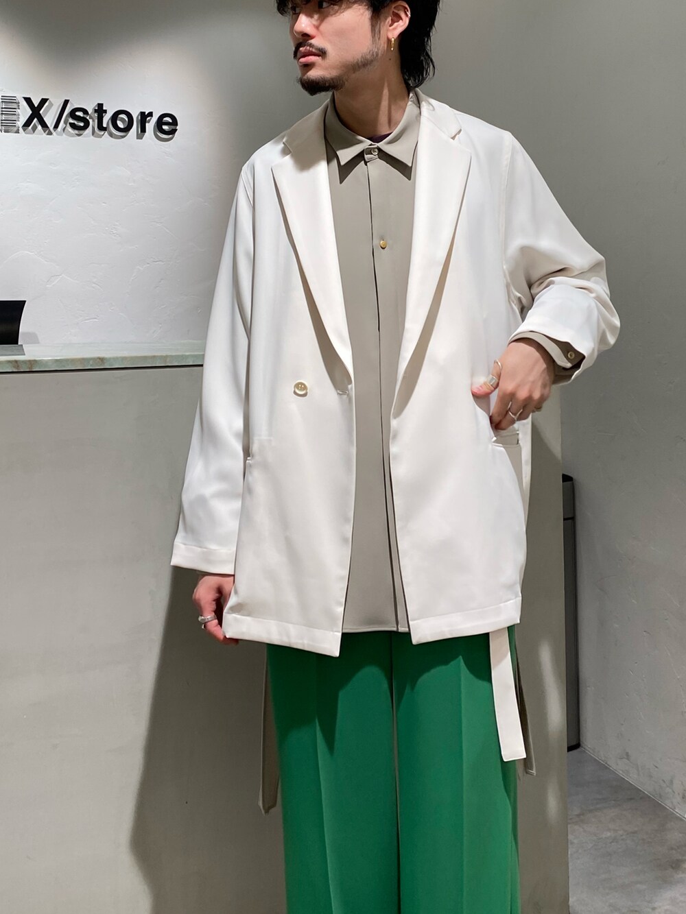 ホワイト系のテーラードジャケット、ベージュ系のトップス、グリーン系のスラックスを着用したメンズの春コーディネートの2枚目の写真