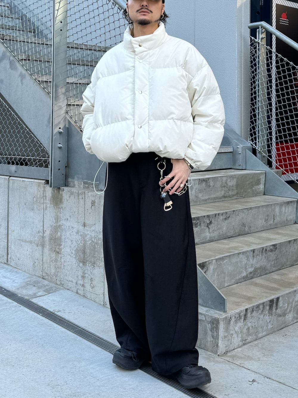 ホワイト系のブルゾン、ブラック系のスラックス、レッド系のニット/セーターを着用したメンズの冬コーディネートの2枚目の写真