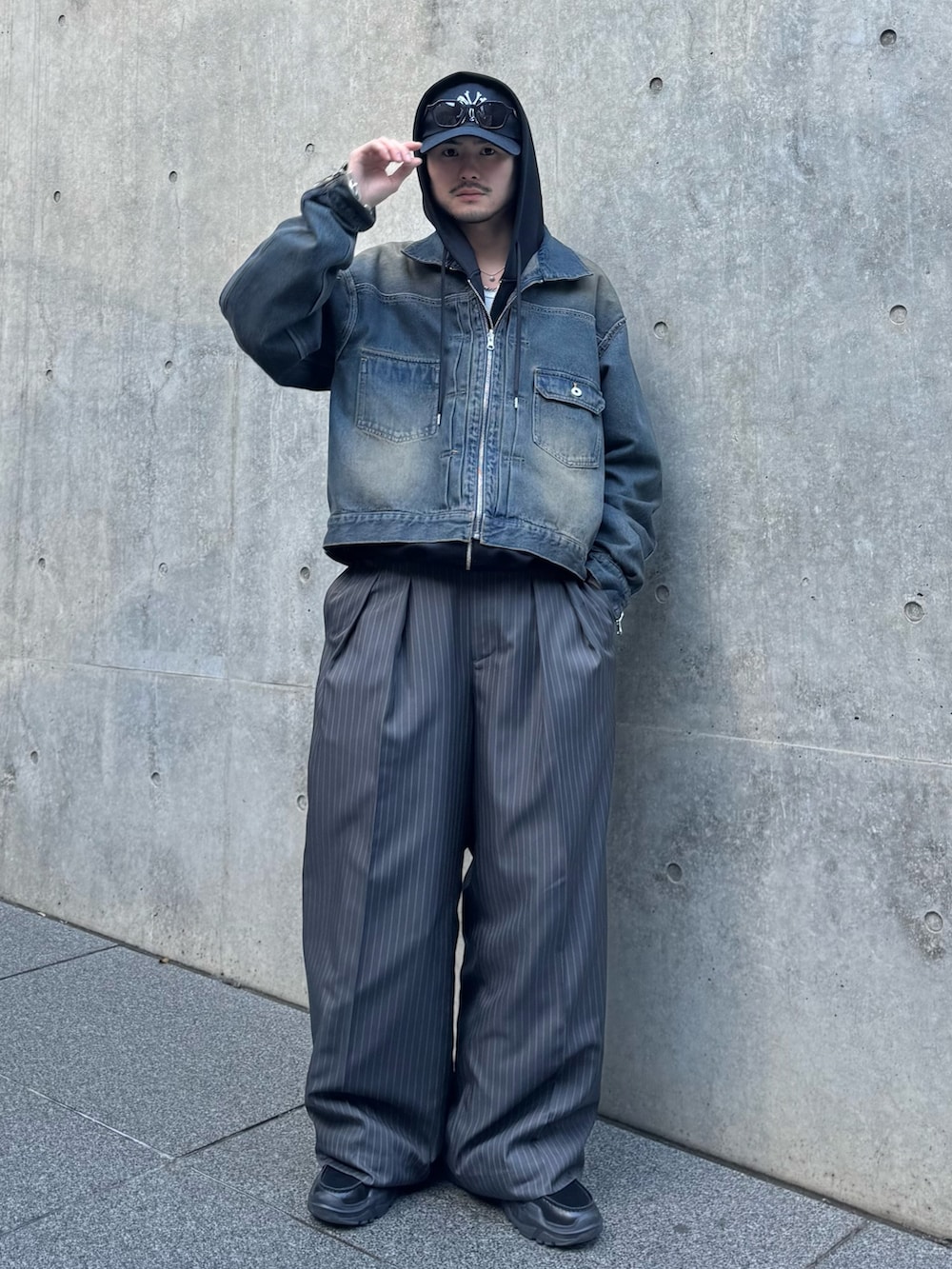 ブラック系のパーカー、ブルー系のデニムジャケット、グレー系のスラックスを着用したメンズの冬コーディネートの5枚目の写真