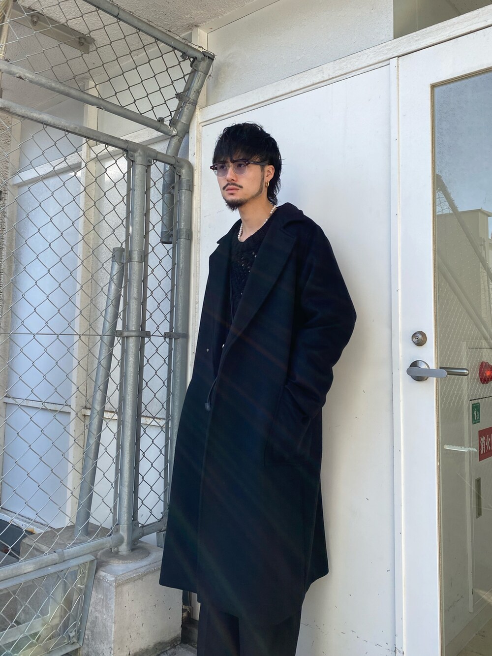 ブラック系のチェスターコート、ブラック系のニット/セーター、ブラック系のスラックスを着用したメンズの冬コーディネートの4枚目の写真