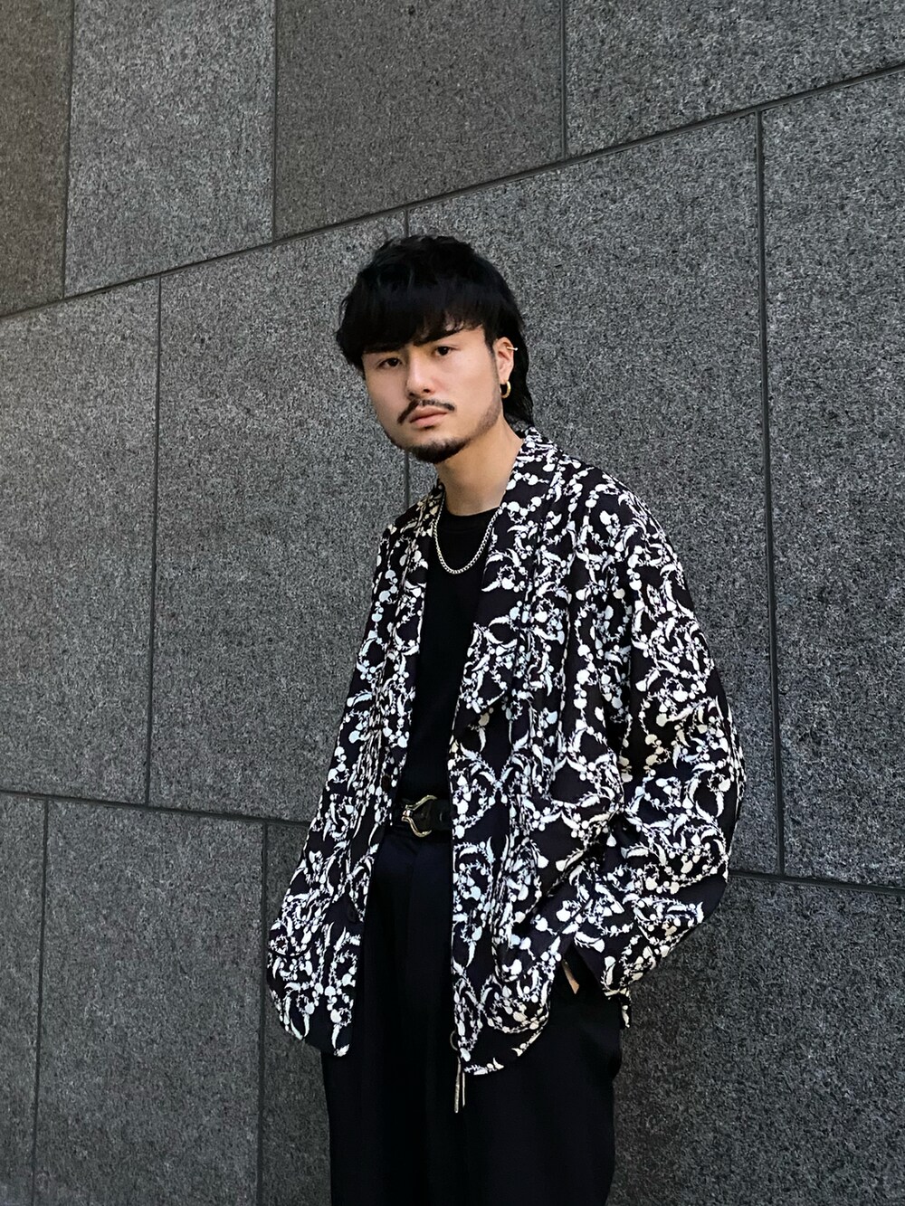 ブラック系のテーラードジャケット、ブラック系のスラックス、ブラック系のサンダルを着用したメンズの春コーディネートの3枚目の写真