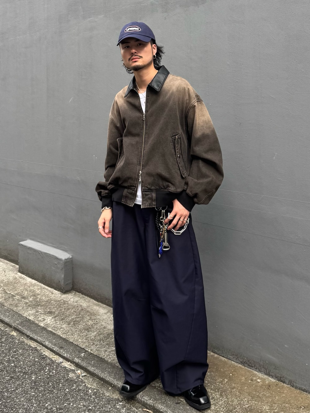 ブラウン系のデニムジャケット、ブルー系のスラックス、ブルー系のキャップを着用したメンズの秋コーディネートの2枚目の写真