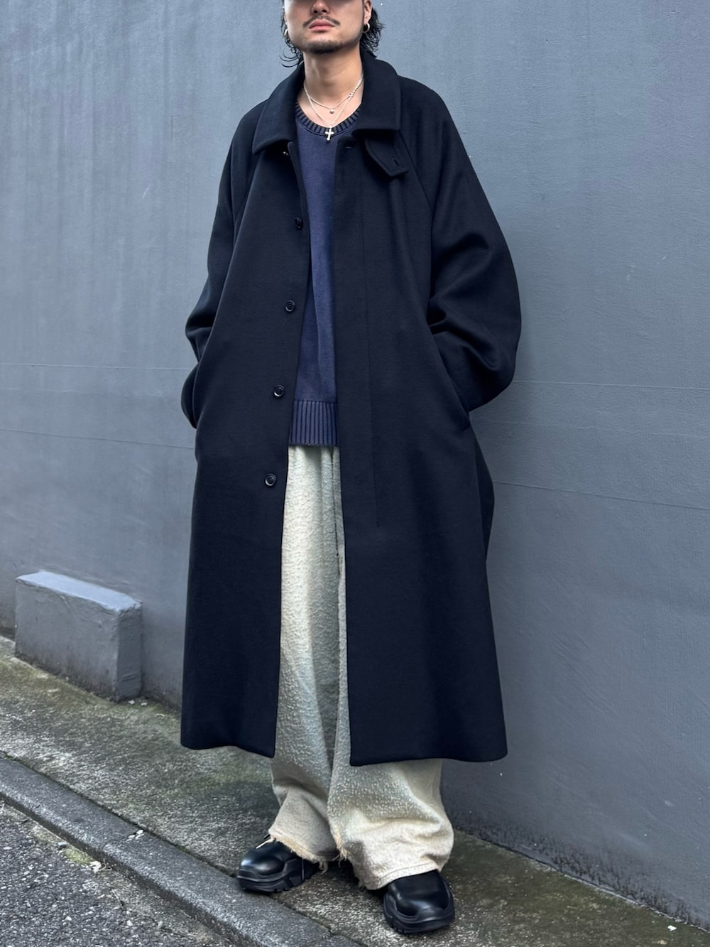 ブルー系のニット/セーター、ブルー系のデニムパンツ、ブラック系のステンカラーコートを着用したメンズの秋コーディネートの3枚目の写真