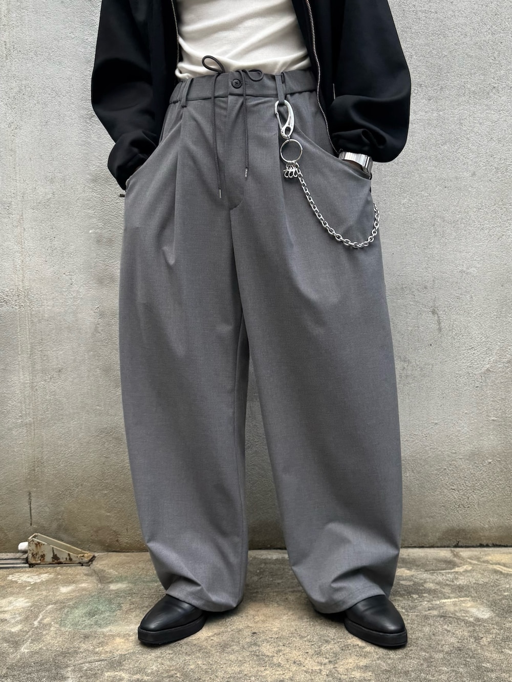 ブラック系のパーカー、グレー系のスラックス、シルバー系のウォレットチェーンを着用したメンズの秋コーディネートの9枚目の写真