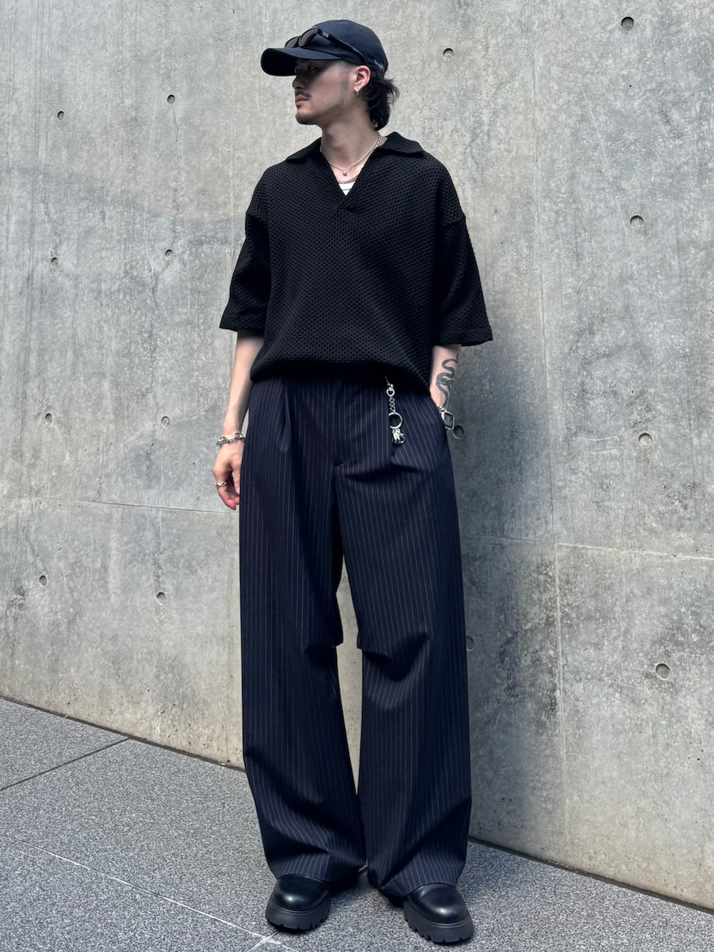 ブラック系のニット/セーター、ブラック系のその他シューズ、ブルー系のスラックスを着用したメンズの夏コーディネートの2枚目の写真