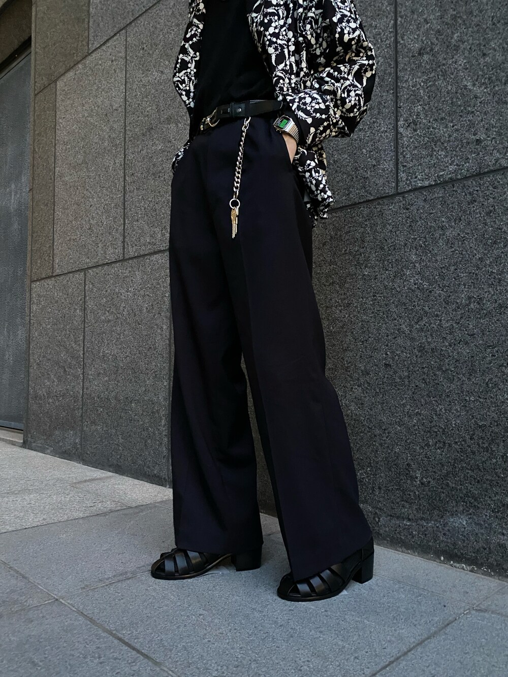 ブラック系のテーラードジャケット、ブラック系のスラックス、ブラック系のサンダルを着用したメンズの春コーディネートの5枚目の写真