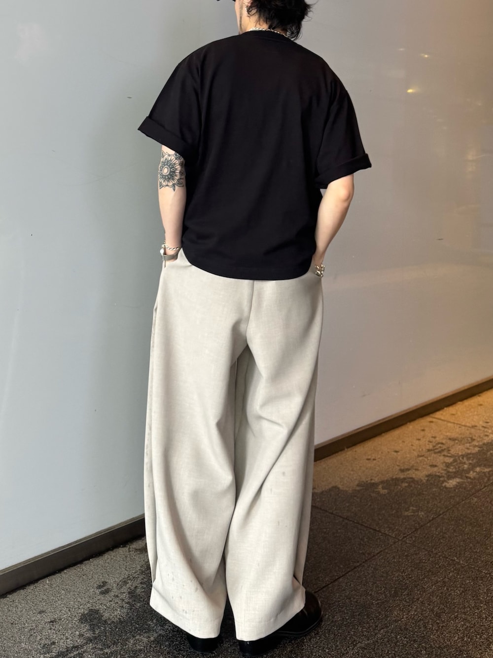 ブラック系のTシャツ/カットソー、ベージュ系のスラックスを着用したメンズの春コーディネートの4枚目の写真